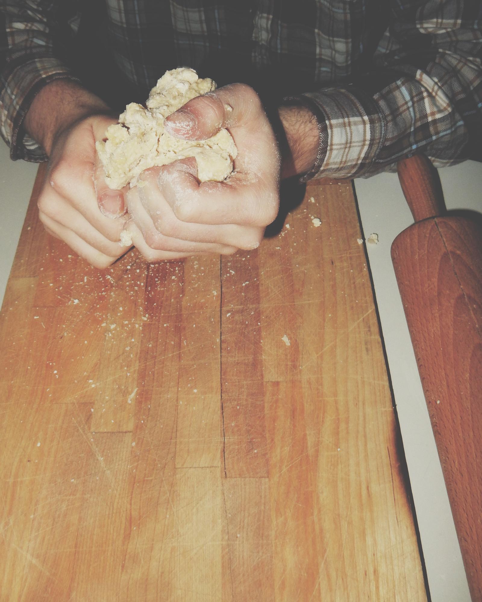 Dettaglio mani che impastano pane artigianale su tavolo di legno