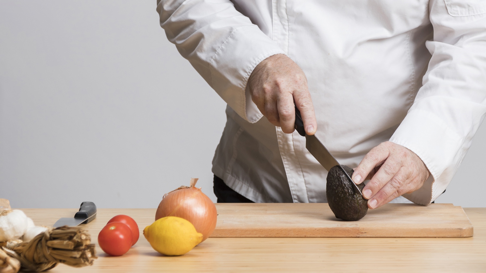 Chef al tavolo che affila coltello e prepara ingredienti freschi